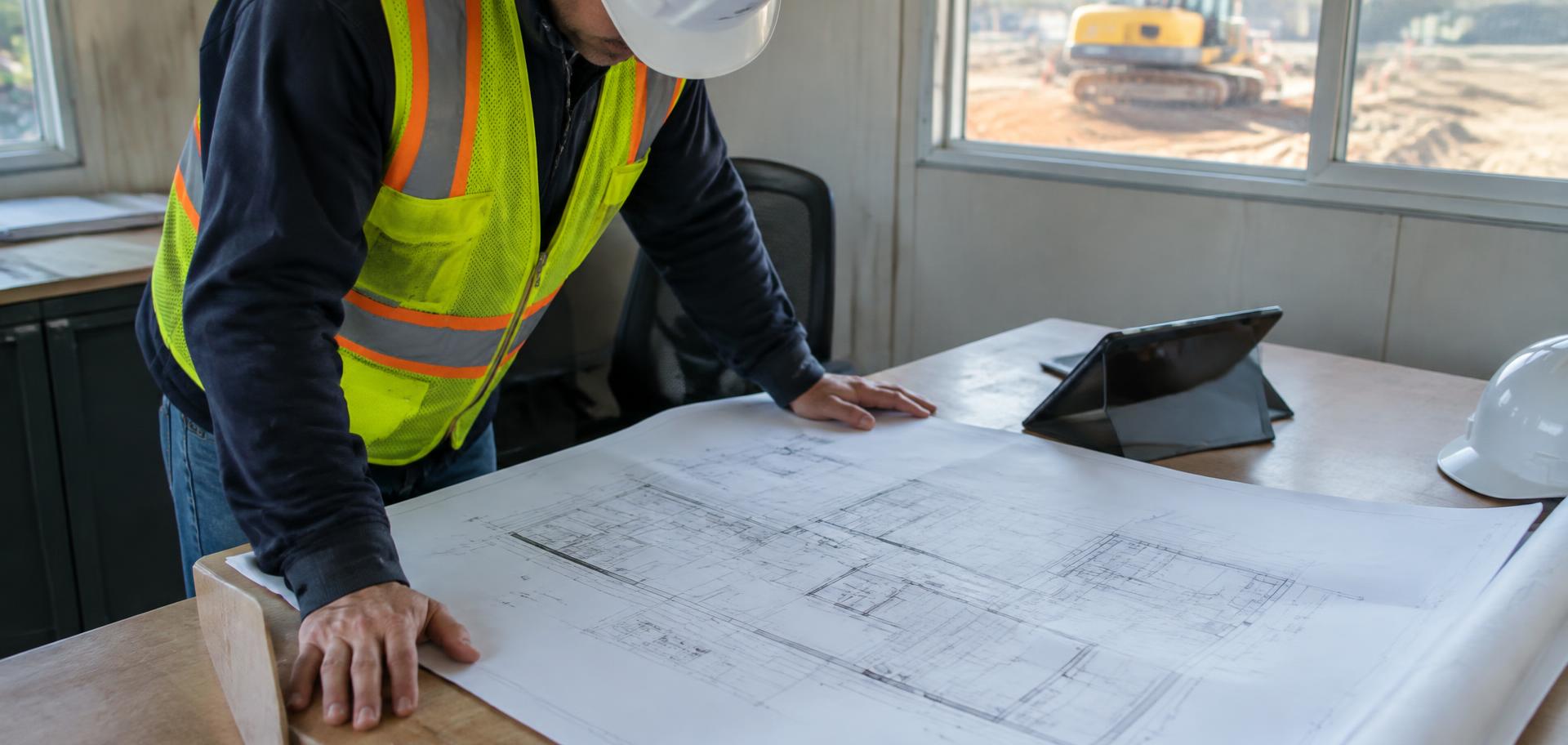 Project manager reviewing construction drawings at a job site office